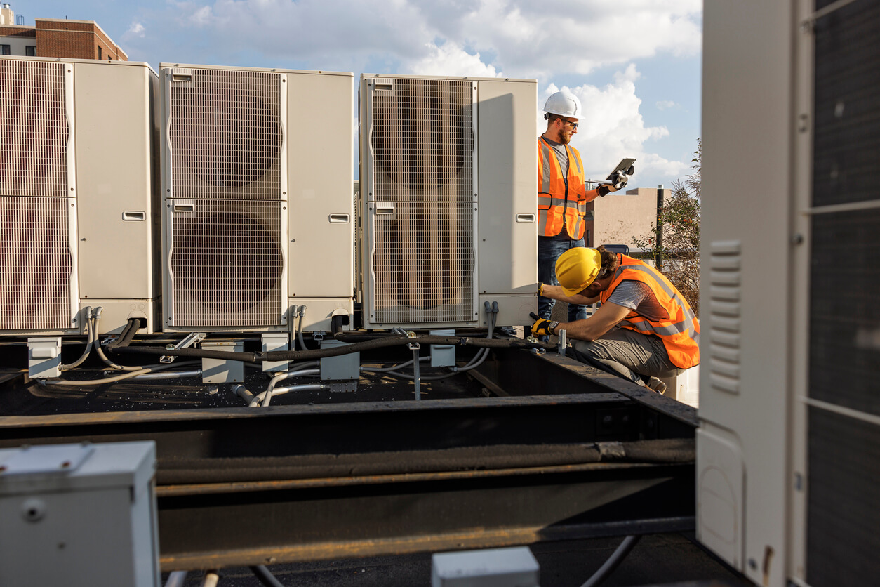 Two workers on rooftop with equipment